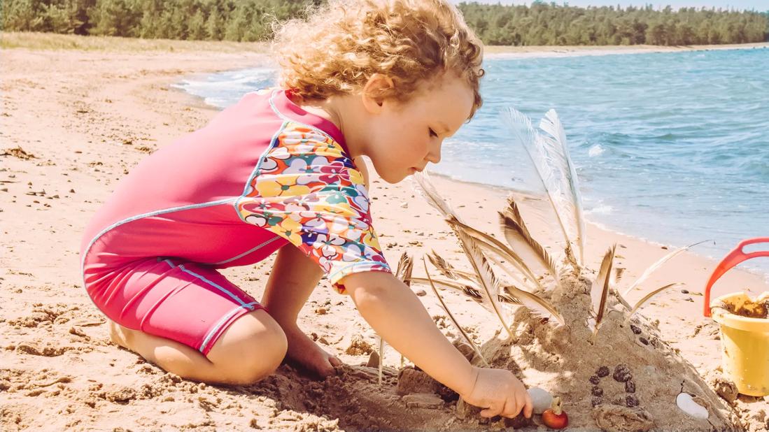 Child dressed in UPF clothing while playing at beach