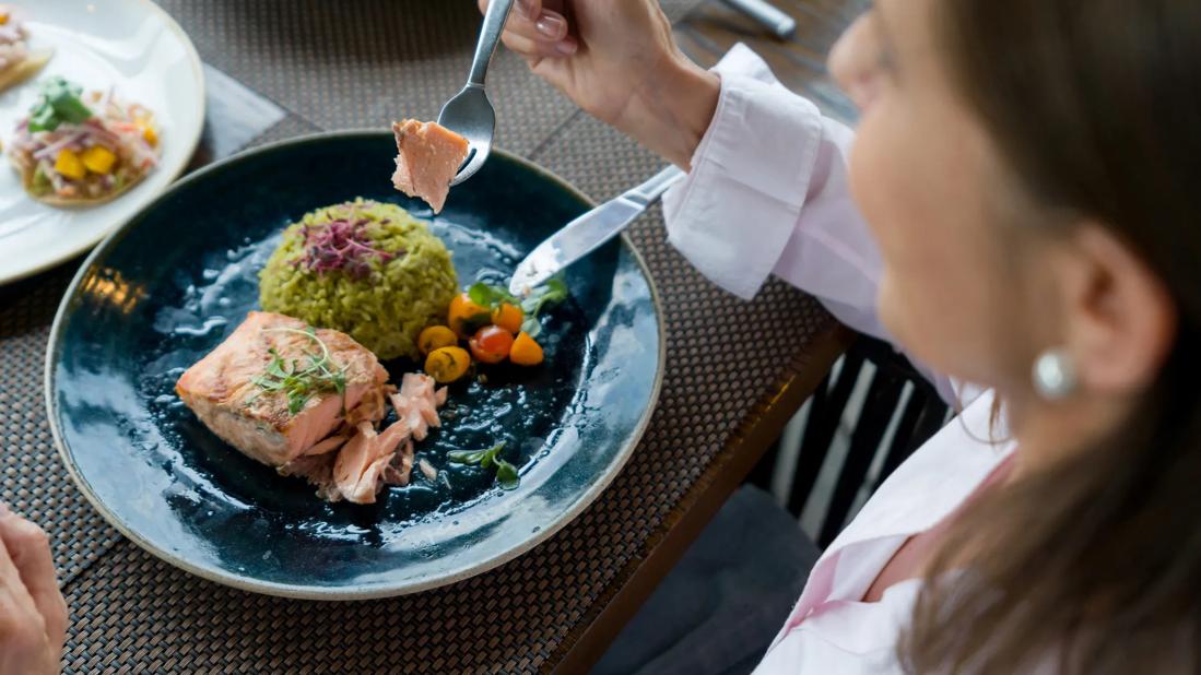 Person eating healthy meal of salmon, rice and veggies