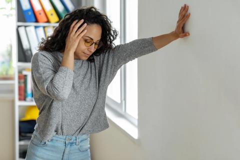Person leaning against wall, holding their head