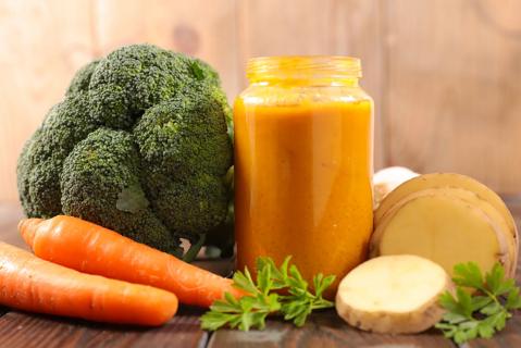 Mason jar of pureed vegetables with broccoli, carrots and potatoes around it