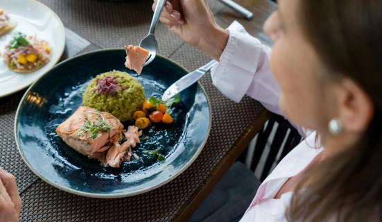 Person eating healthy meal of salmon, rice and veggies