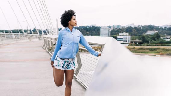 Person paused on pedestrian bridge, stretching their quads